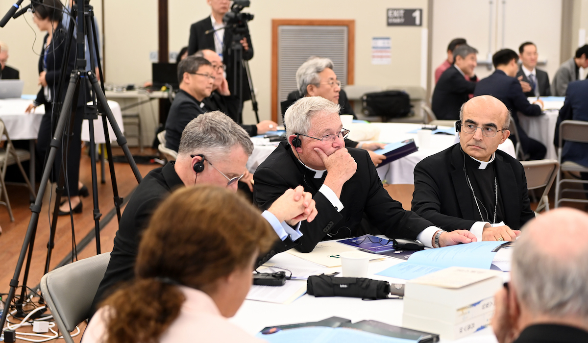 bishops sit together at a table as they listen to a speaker at the peace forum